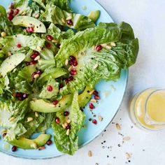 a blue plate topped with lettuce and pomegranate next to a glass of orange juice