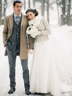 a couple standing next to each other in the snow with marshmallows on them