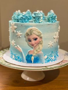 a frozen princess cake with blue frosting and flowers on the top is sitting on a plate