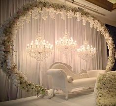 a white couch sitting under a chandelier surrounded by flowers