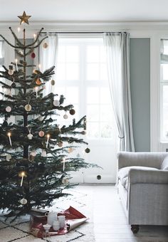 a living room with a christmas tree in the corner and other decorations on the floor