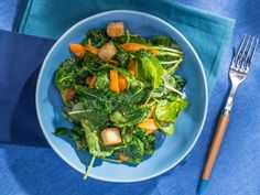 a blue bowl filled with salad and croutons on top of a blue table cloth