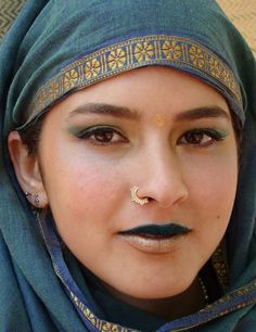 a close up of a woman with a nose ring and green scarf around her head