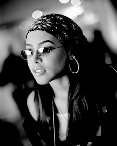 a black and white photo of a woman with glasses wearing a bandana on her head