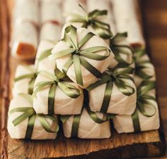 many wrapped presents are stacked on top of each other and tied with green ribbon around them