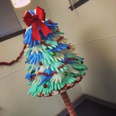 a christmas tree made out of plastic gloves and red bow on it's head