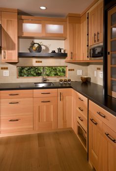 a kitchen with wooden cabinets and black counter tops in the center, along with wood flooring