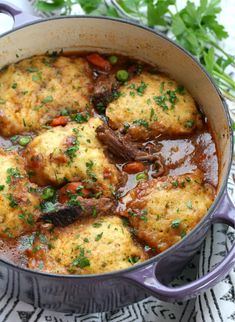 a pot filled with meat and vegetables on top of a table next to parsley