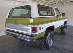 a green and white pick up truck parked in a garage