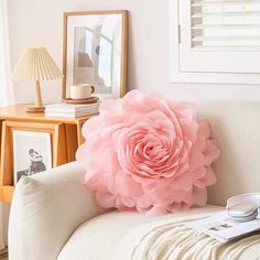 a large pink flower sitting on top of a white couch next to a lamp and pictures