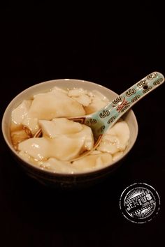 a bowl filled with dumplings on top of a black table next to a spoon