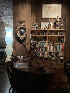 a room with a table, bookshelf and shelves filled with various items on it