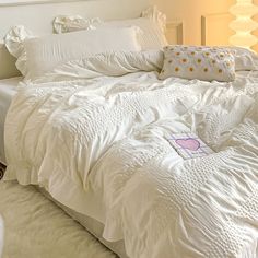 an unmade bed with white comforter and pillows on top of it in a bedroom