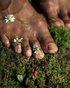 a person's feet covered in dirt and grass with small flowers on their toes