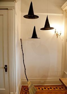 three witches hats hanging from the ceiling above a broom in front of a white wall