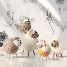 four sheep are standing next to each other in front of a snow covered mountain backdrop