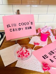 pink candy bar signs on a table with hearts and candies in a glass bowl