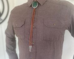 This awesome bolo tie has a southwestern design and green agate centerpiece. The cord is genuine leather. All the stones will vary slightly. Our bolos pair nicely with many of our belt buckles! They make wonderful gifts. The western bolo tie rope length is 39'' ; charm agate stone pendant size is 2'' x 1 1 /2'' Western Lariat Bolo Ties For Rodeo, Western Bolo Ties With Adjustable Length, Western Lariat Bolo Tie For Rodeo, Western Style Lariat Bolo Tie For Rodeo, Western Style Adjustable Bolo Ties, Handmade Artisan Bolo Ties For Western-themed Events, Adjustable Western Bolo Tie With Concho, Handmade Adjustable Western Bolo Ties, Western Lariat Bolo Ties For Western-themed Events