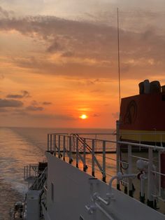 the sun is setting over the ocean on a boat