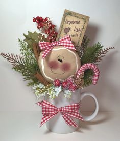 a coffee mug filled with christmas decorations and a teddy bear on the front, sitting next to a book