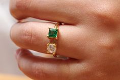 a woman's hand with a ring on it and an emerald stone in the middle