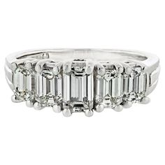 an emerald cut diamond ring with five baguets on the side and three rows of diamonds