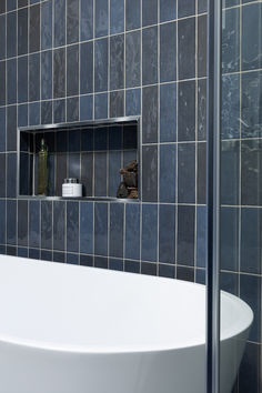 a bath tub sitting under a window next to a shelf filled with bottles and vases