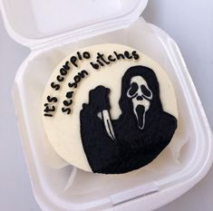 a decorated cake in a foam container with writing on the side and a silhouette of a person holding a knife