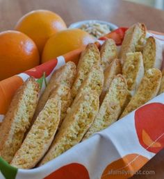 oranges and bread sticks in a basket on a table