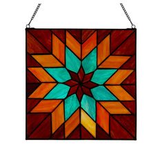 a colorful stained glass window hanging from a chain on a white wall with an orange and blue star design