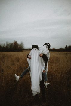 two people dressed as ghost hugging in a field