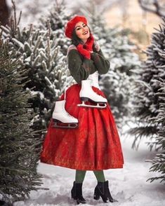 a woman in a red dress and hat is standing in the snow