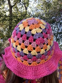 a close up of a person wearing a pink and purple crocheted hat with flowers on it