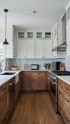 a kitchen with white cabinets and wood floors