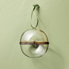 a glass ball hanging on a wall with a green cord attached to the top of it