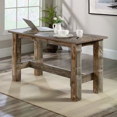 a wooden table with a laptop and coffee cup on it in front of a window