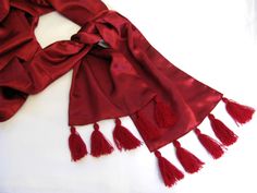 a red scarf with tassels laying on a white surface