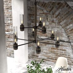 a chandelier with candles hanging from it's sides in front of a brick wall