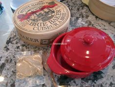 a red casserole dish sitting on top of a counter next to a container