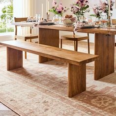 a dining room table and bench with flowers in vases