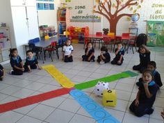 children are sitting on the floor playing with blocks and numbers in a classroom setting, while adults watch