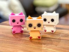 three paper toy cats sitting on top of a wooden table