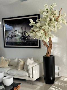 a vase with flowers in it sitting on the floor next to a couch and coffee table