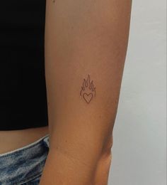 a woman's arm with a small heart tattoo on the left side of her arm