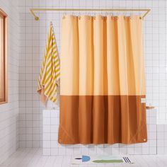 an orange and yellow shower curtain in a bathroom with white tile flooring on the walls