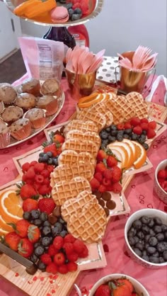 a pink table topped with waffles and fruit