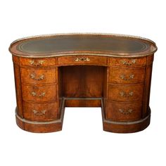 an antique wooden desk with drawers and leather trimmings on the top, against a white background