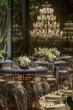 a dining room set up for a formal event with chandelier and blue linens