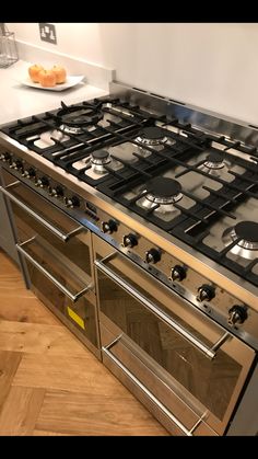 a stove top oven sitting inside of a kitchen next to a wooden floor and white walls