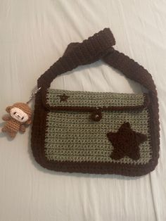 a crocheted purse with a teddy bear hanging from the handle on top of it